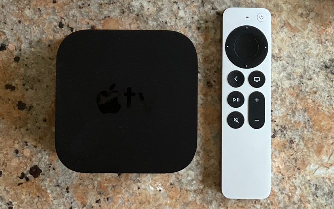 Apple TV 4K box and remote on stone counter top.