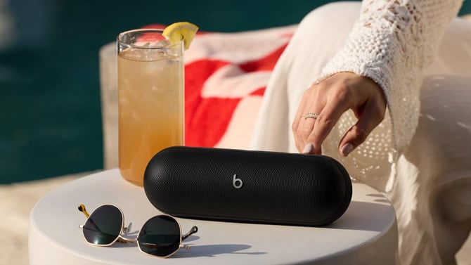 A Beats Pill sits on a table next to sun glasses