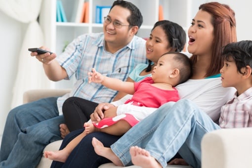 Family of five watching TV on couch