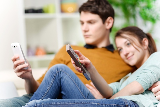 Man watching smartphone; woman watching TV