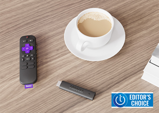 The Roku Streaming Stick 4K sits on a table with a remote and cup of coffee. The Techlicious Editor's Choice Award logo is in the lower right corner.
