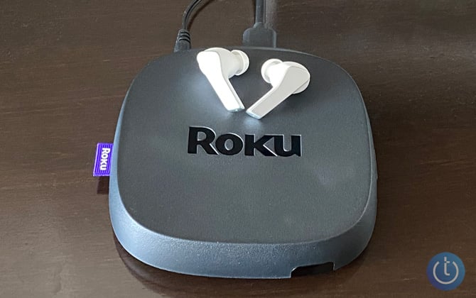 Roku Ultra 2022 model with white Lenovo Smart Wireless Earbuds on top.