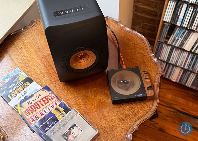 The Syitren R300 is shown with some CDs and a KEF LS50 Wireless II speaker