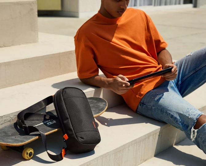 tomtoc Sling Crossbody Bag for Nintendo Switch 2 rests on a skateboard for scale