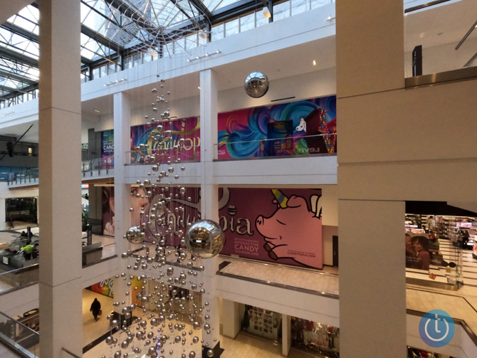 Image taken by GoPro Hero10 with ISO 1600 and saved in the camera as a JPEG file. The scene is looking down and across a mall courtyard with a reflective ball art installation hanging down from the ceiling.