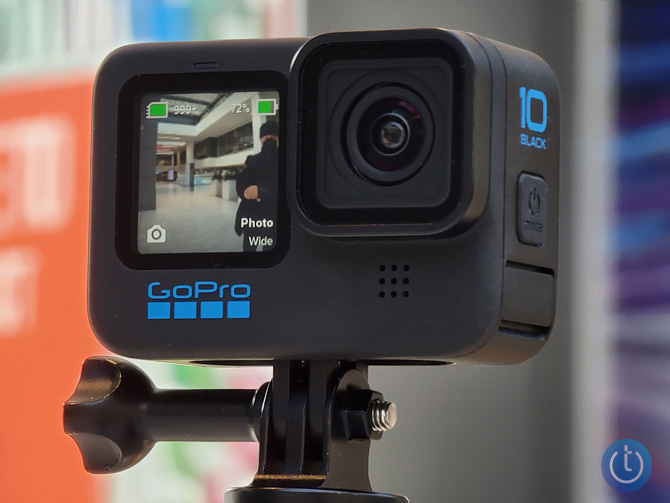 GoPro Hero10 Black mounted on a selfie stick with a colorful blurred out background.