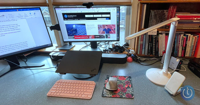 Andrea Smith's home office from the left: two monitors (one showing the Techlicious website), a laptop stand with a Lenovo Thinkpad laptop, the Logitech MX Mini keyboard, Logitech MX Master 3 mouse, OttLite lamp, Infinity Lab InstantStation charger, Techlicious logo. 
