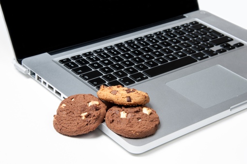Baked chocolate chip cookies sitting on top of a laptop computer
