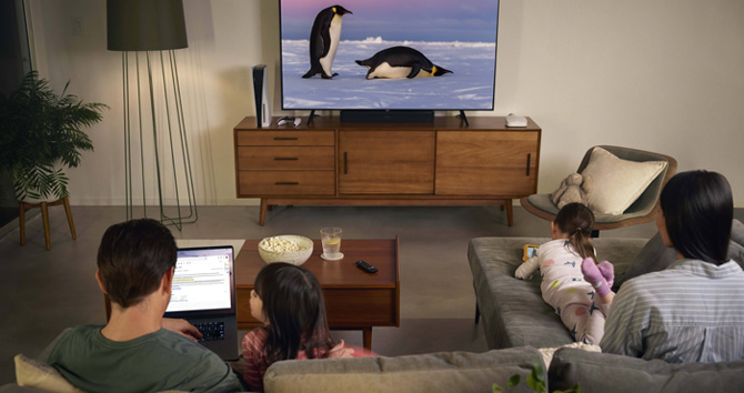 eero Pro 6E shown next to a TV in a living room setting with a family of four using electronic devices.