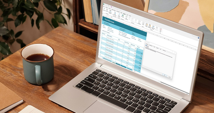 Desk with a coffee mug and a laptop showing a Microsoft Excel spreadsheet with a popup window that shows the option to lock cells.