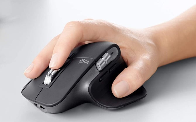 Logitech MX Master 3 Wireless mouse with hand on white surface