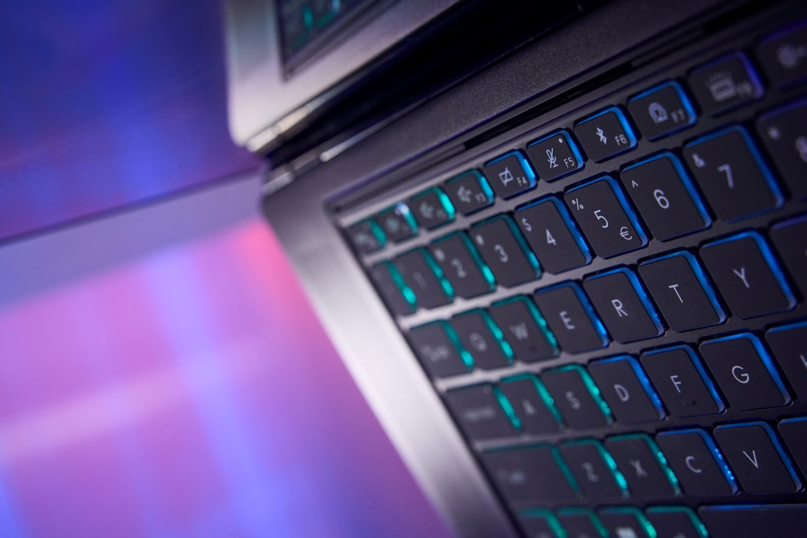 Close-up of the MSI Stealth 16 AI+ keyboard, with blue and teal backlighting glowing around the keys.