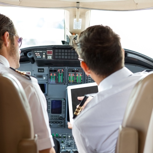 Pilots in plane cockpit using tablet