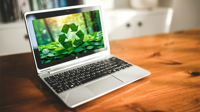 Computer recycling concept with a laptop that is displaying a recycling symbol made of leaves.