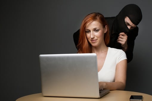 Thief looking over woman's shoulder at computer