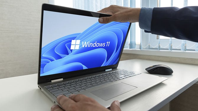 Hands opening a Windows 11 laptop