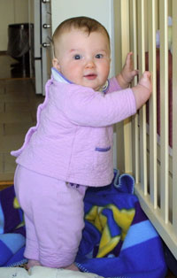 baby standing against crib