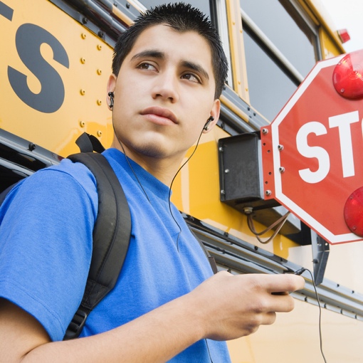Boy next to a school bus with headphones