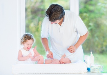 Dad and daughter changing a baby's diaper