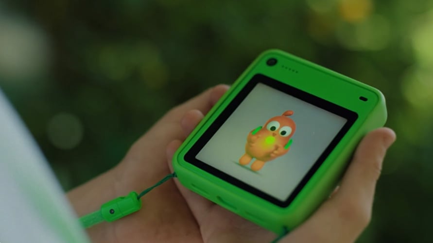 Child holding a green Freckle device with an orange cartoon character on its screen.