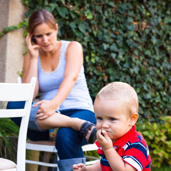 mother distracted by cellphone - Shutterstock