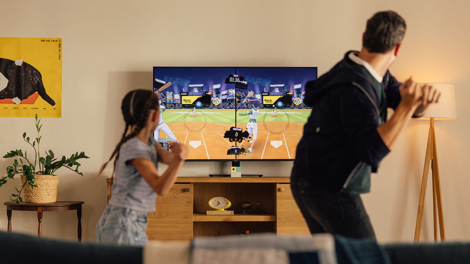 An adult and child mimic swinging baseball bats while playing a Nex Playground game on a living room TV.