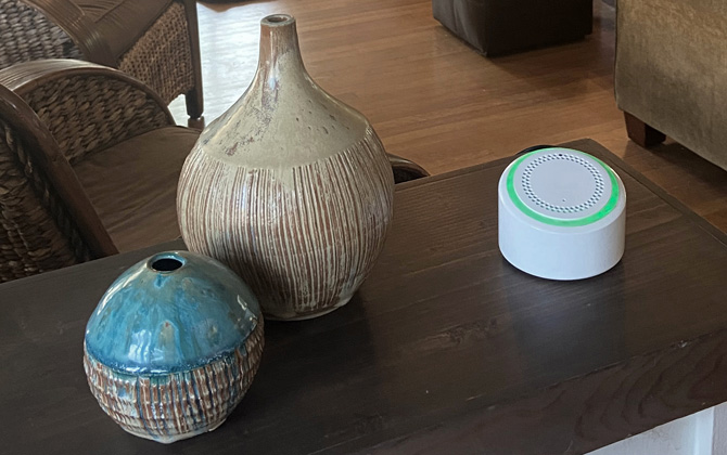 AerNos AerHome sitting on a wood table with two ceramic vases. 