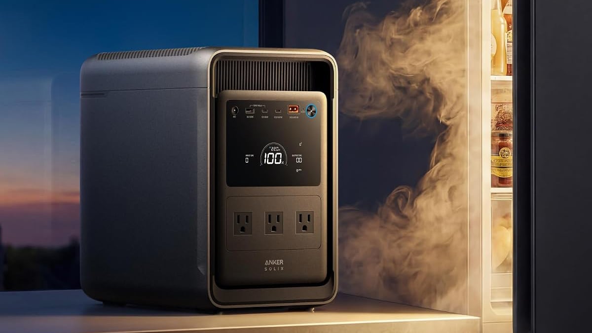 Anker SOLIX S2000 portable power station beside an open refrigerator, with its display showing 100% charge.
