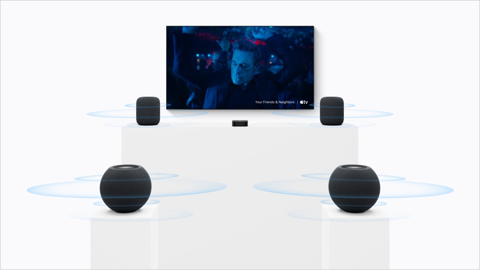 Apple TV 4K beneath a television, with two HomePod speakers beside the screen and two HomePod minis behind the viewing area. Blue rings illustrate sound spreading from each speaker.