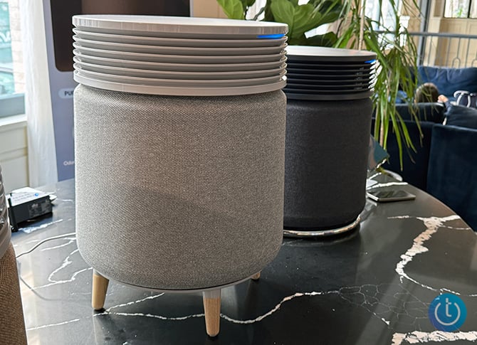 Blueair Blue Signature shown with wooden legs and a light fabric. Behind it, you can see another Blue Signature with a black wrap and no legs.