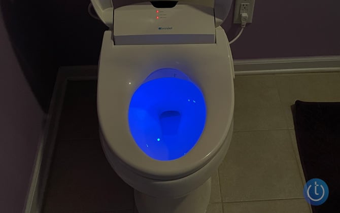 Brondell Swash 1400 shown in semi-darkness, which highlights the blue LED light seen in the toilet bowl.