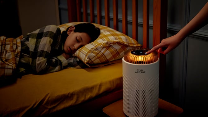 Coway Airmega 50 sits on a nightstand with the light ring in nightlight mode.