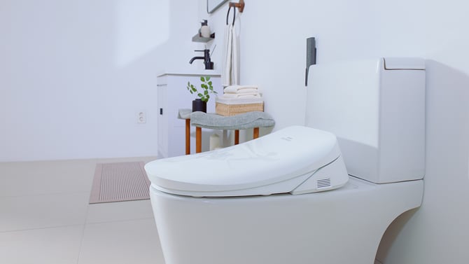 Coway Bidetmega 500 S is shown from the side with its gray remote control wall-mounted next to it.