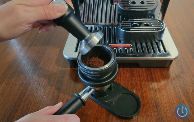 Hand hold tamper and portafilter with funnel and ground coffee beans. 
