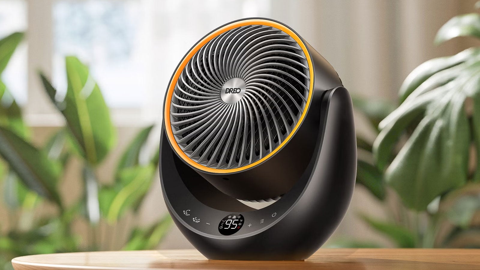 Black DREO DR-HSH015 space heater with a circular fan grille, orange trim, and digital temperature display sitting on a wooden table.
