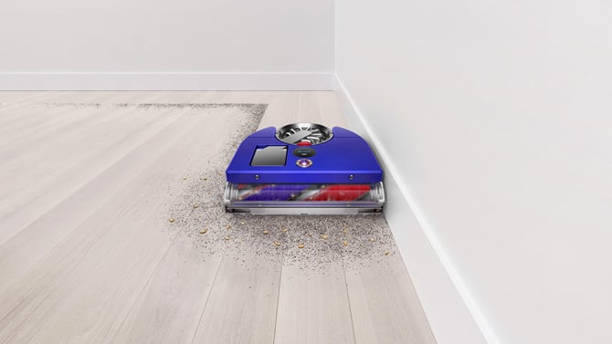 Dyson 360 Vis Nav robotic vacuum shown cleaning next to a wall.