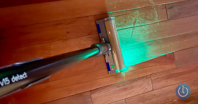 Dyson V15 Detect seen from the top with the green light illuminating particles on a wood floor