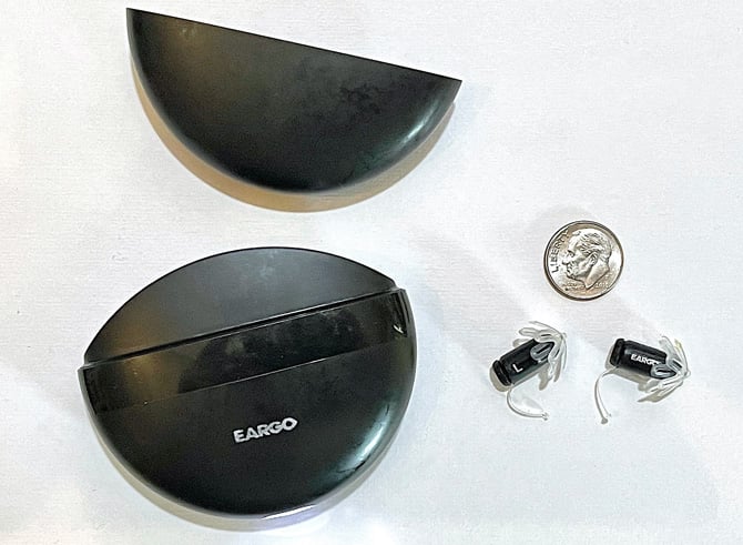 Eargo 5 case open with the Eargo 5 buds to the right and a dime for scale.