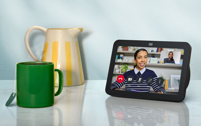 Amazon Echo Show 8 Gen 3 showing a video chat on the screen. To the left are a pitcher and mug with a tea bag for scale.