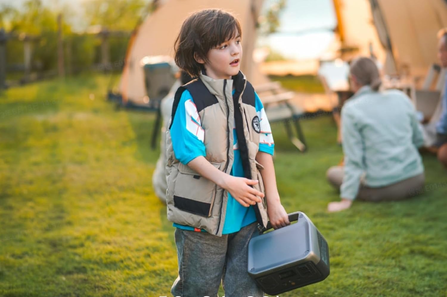 Child carrying an EcoFlow RIVER 2 portable power station at a grassy campsite.