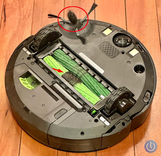 iRboto Roomba Combo j7+ shown with the bottom facing up. In a red circle you see the bee hive of hair and hair entrwined in the rollers is pointed out.