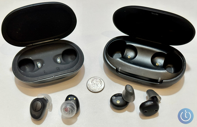 Sony CRE-E10 shown outside of their case to the right of the Jabra Enhance Plus, also shown outside their case. A dime is in the picture for scale.