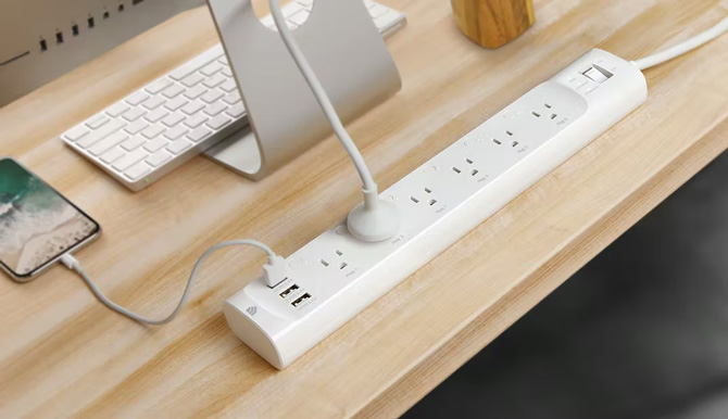 Kasa Smart Plug Power Strip on desk with Mac, keyboard, and iPhone plugged into a USB port.