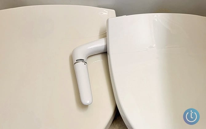 Closeup of two Kohler Puretide bidet seats. The one on the left is biscuit and the one on the right is white.