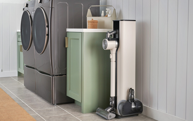 LG CordZero Stick Vacuum with All-in-One Tower in mudroom to the right of a laundry pair and cabinet with cleaning supplies on top.
