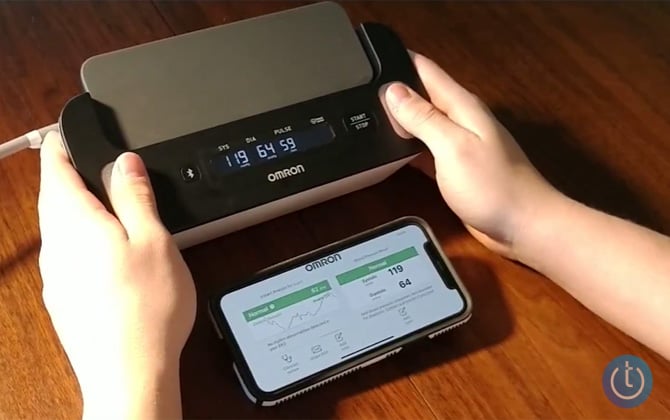 Omron Complete with phone showing EKG and normbal blood pressure highlights with a green bar. 