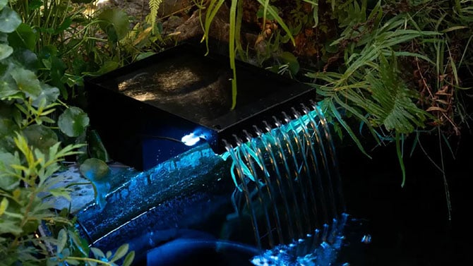 Poposoas LED waterfall flowing into pond showing subtle blue lighting