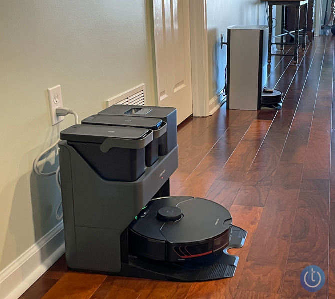 Roborock S7 MaxV Ultra in its base with the Ecovacs Deebot X1 Omni in the background.