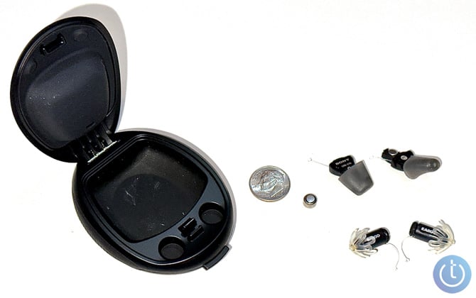 Sony CRE-10 OTC hearing aids out of their case  with the case of the left, a dime, a size 10 battery and the Eargo 5 buds at the bottom.