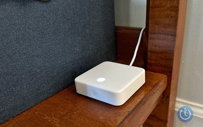 SwitchBot Hub Mini on lower shelf next to blue fabric-covered box.